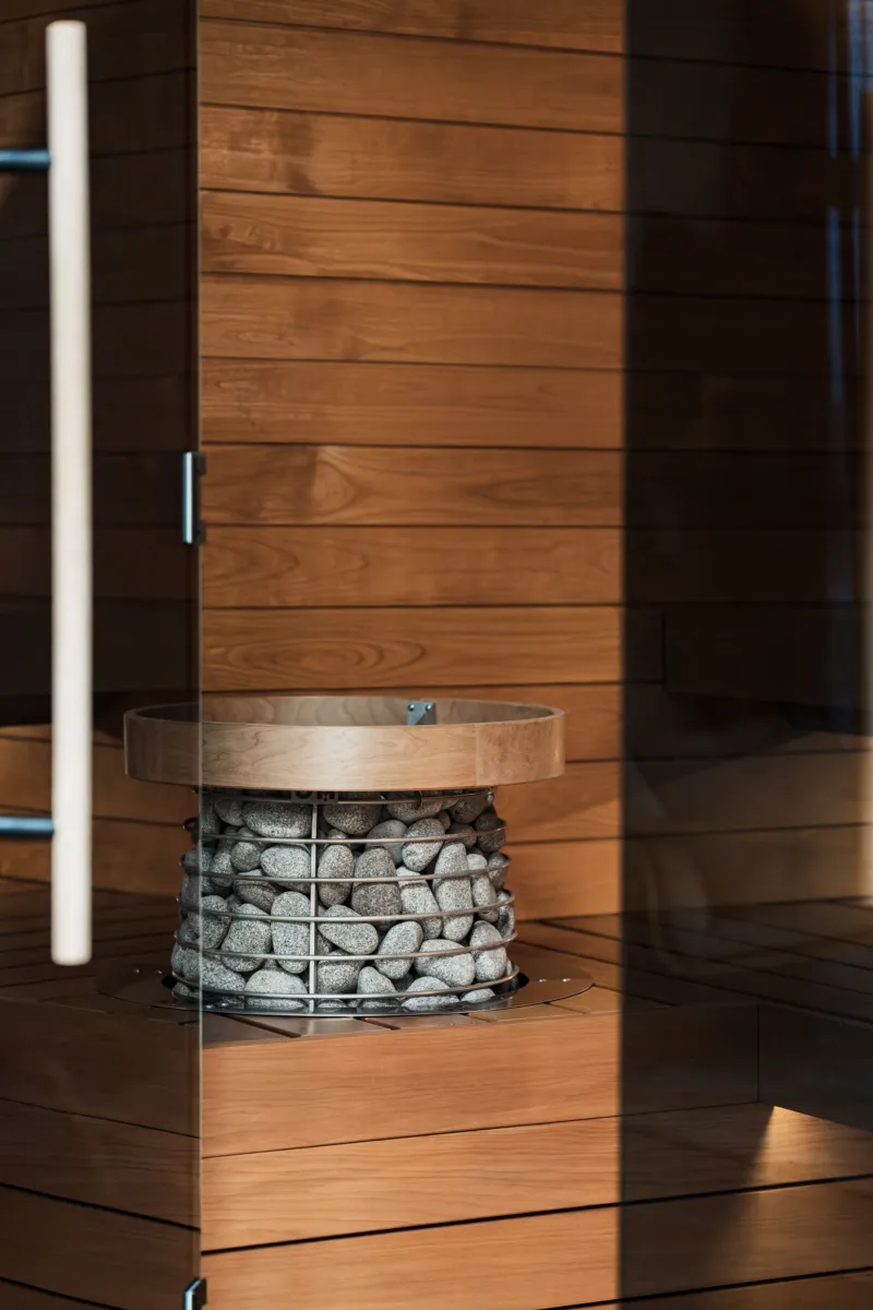 Interior of a modern wood-lined sauna with a stone-topped electric heater